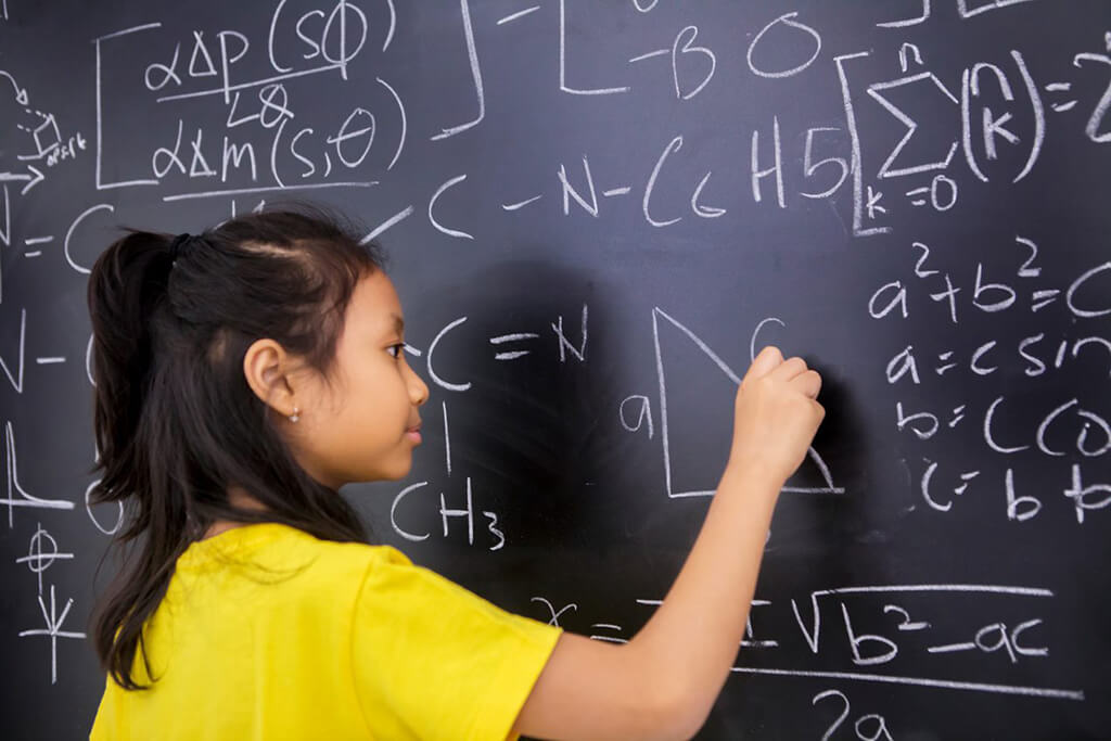 A female student writing math problems on a chalkboard